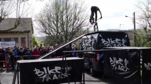 Rider Bike Art en équilibre trial sur le toit du camion, banderole SLA Qu'es Aquò et public de la Cour'SLA Pied 2026