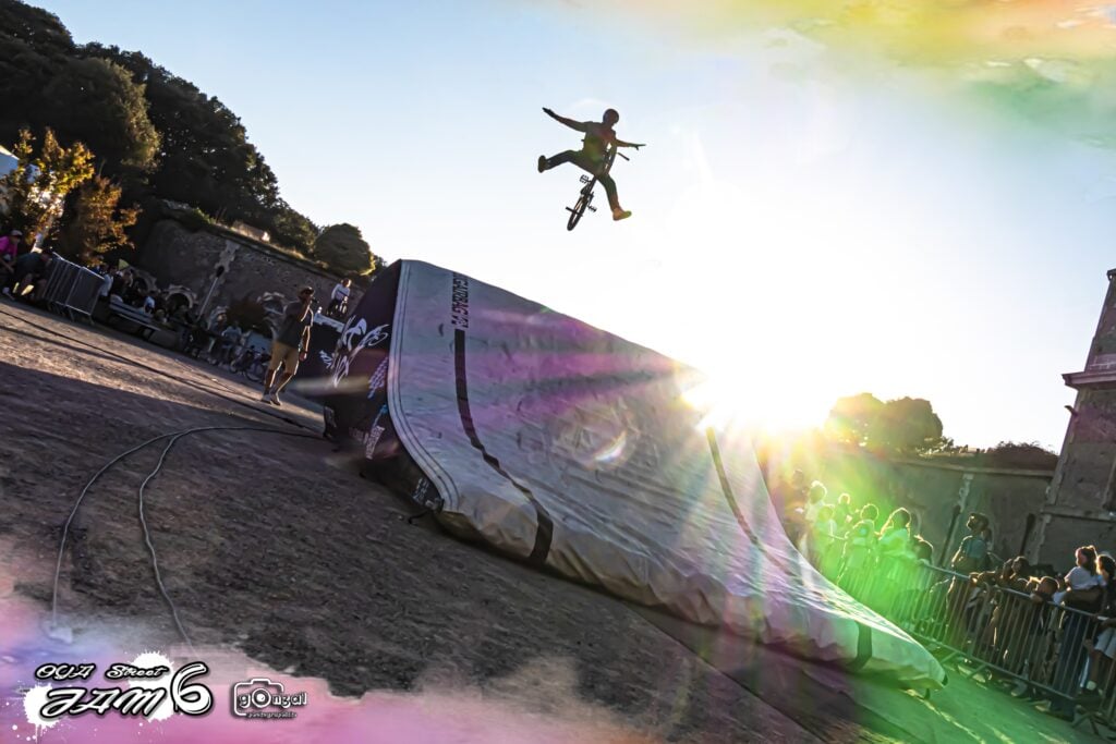 Rider BMX en no foot au coucher du soleil au-dessus du Big Air Bag, public de l'Oya Street Jam