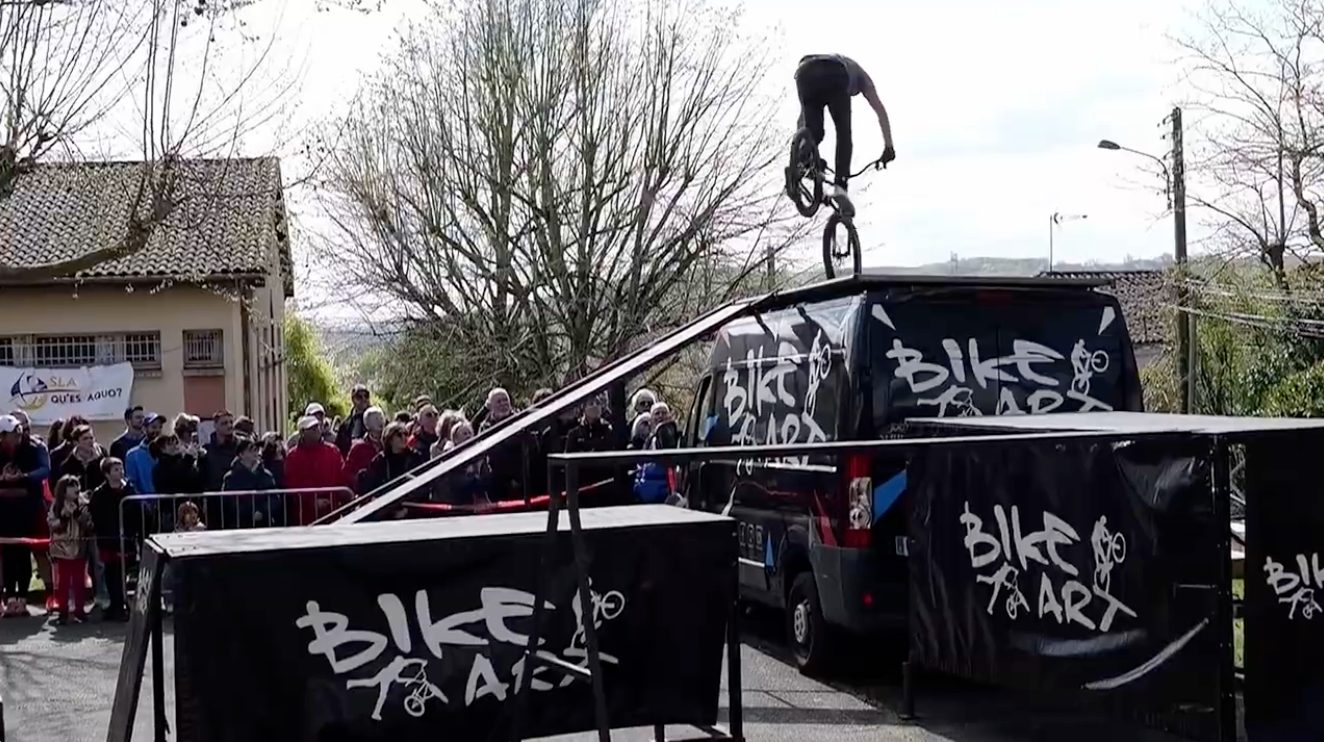 Rider Bike Art en équilibre trial sur le toit du camion, banderole SLA Qu'es Aquò et public de la Cour'SLA Pied 2026